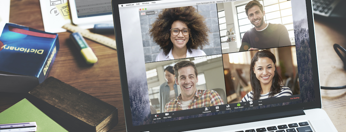 A laptop shows four people in a video conference smiling