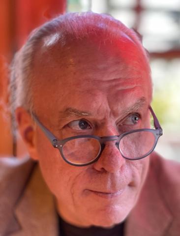 A man with glasses looking over the frames and to the side