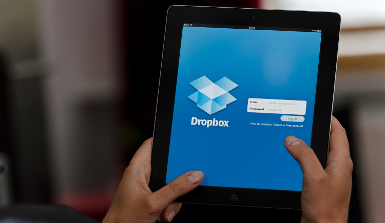 Tablet being held with the Dropbox logo and sign-in dialogue box