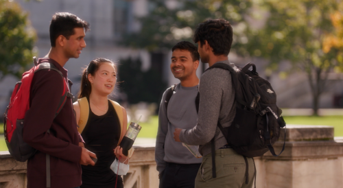 Photo of a group of three people talking to each other outdoors